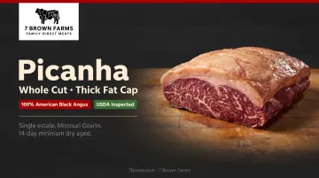 Well-marbled whole picanha cut with thick intact fat cap on butcher block
