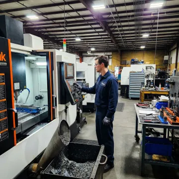 CNC machinist operating a precision metal fabrication machine in a manufacturing facility