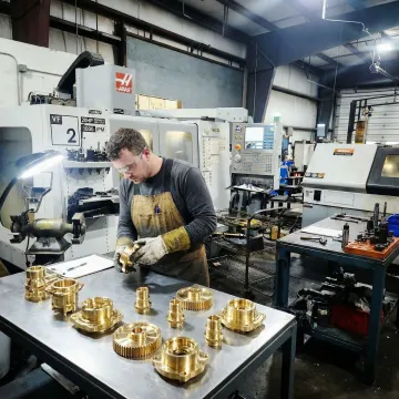 Machinist inspecting brass CNC machined parts during quality control in a machine shop