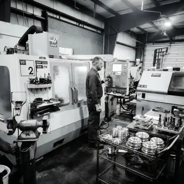 Precision metal machining technician operating CNC equipment in a manufacturing facility