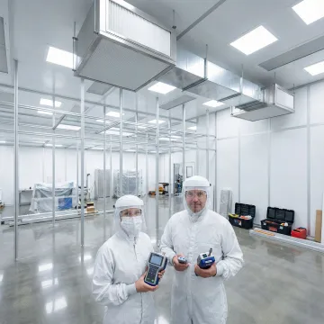 Professional cleanroom construction and performance testing facility with technicians in clean suits