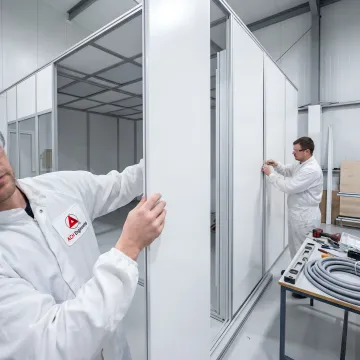 Construction team installing modular cold room panels with refrigeration equipment