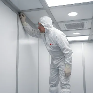 Cleanroom technician in protective gear working in sterile modular cleanroom environment