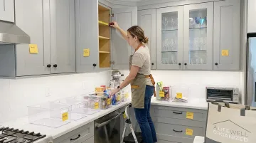 Professional organizer measuring closet space with labeled storage bins