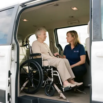 Senior woman smiling comfortably in wheelchair inside clean medical transport vehicle