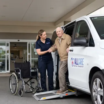 Medical transport specialist helping dialysis patient into wheelchair-accessible vehicle