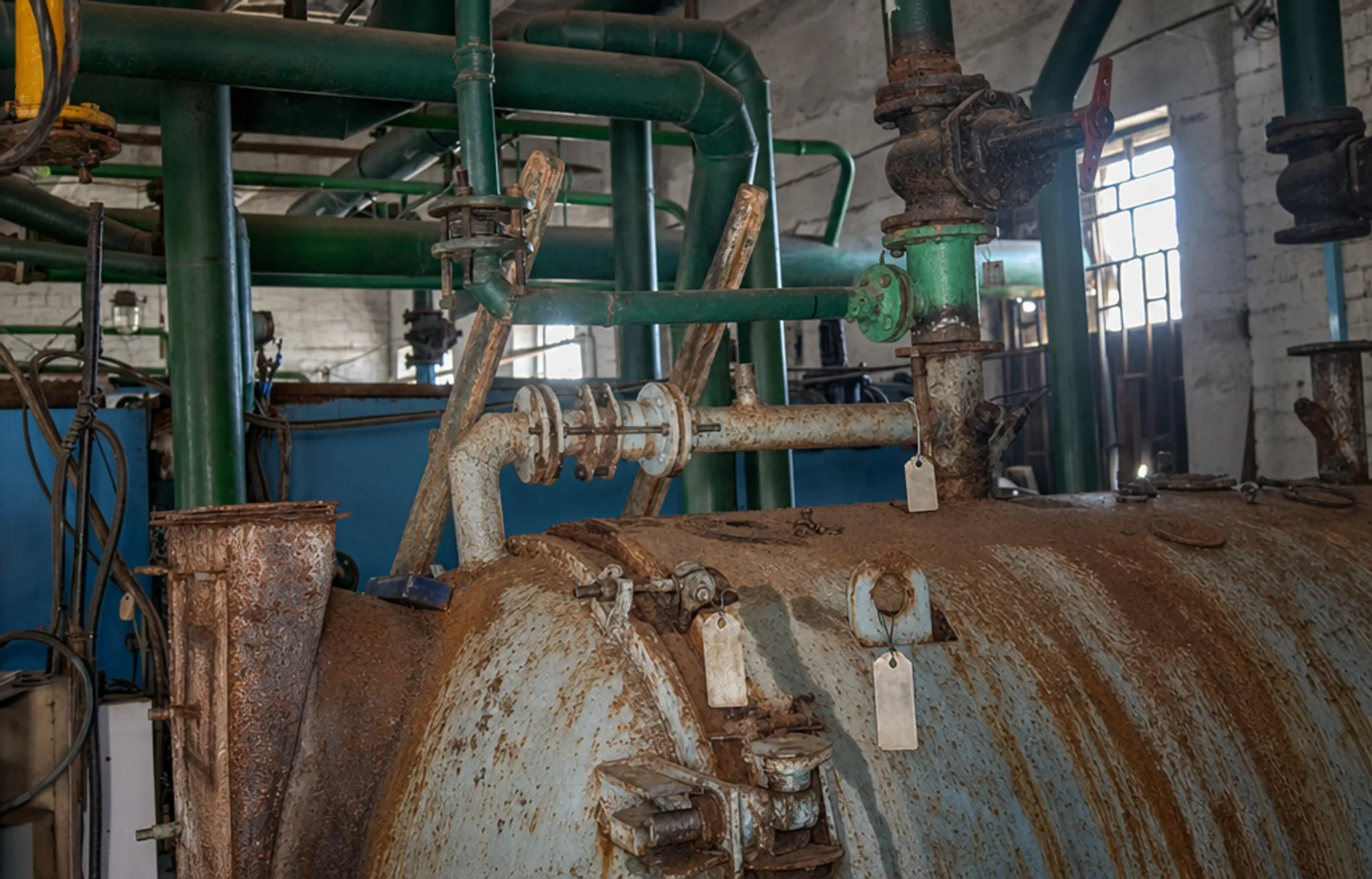 Industrial pressure vessel with visible corrosion and safety inspection tags