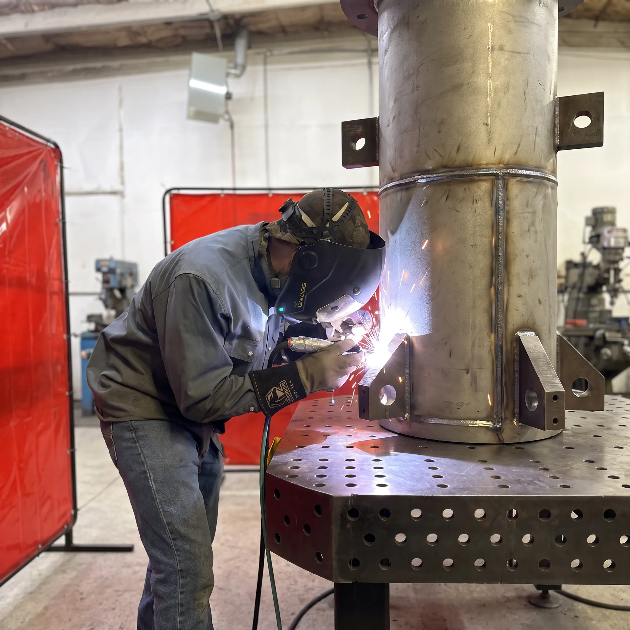 Fabricator welding a custom metal tank assembly