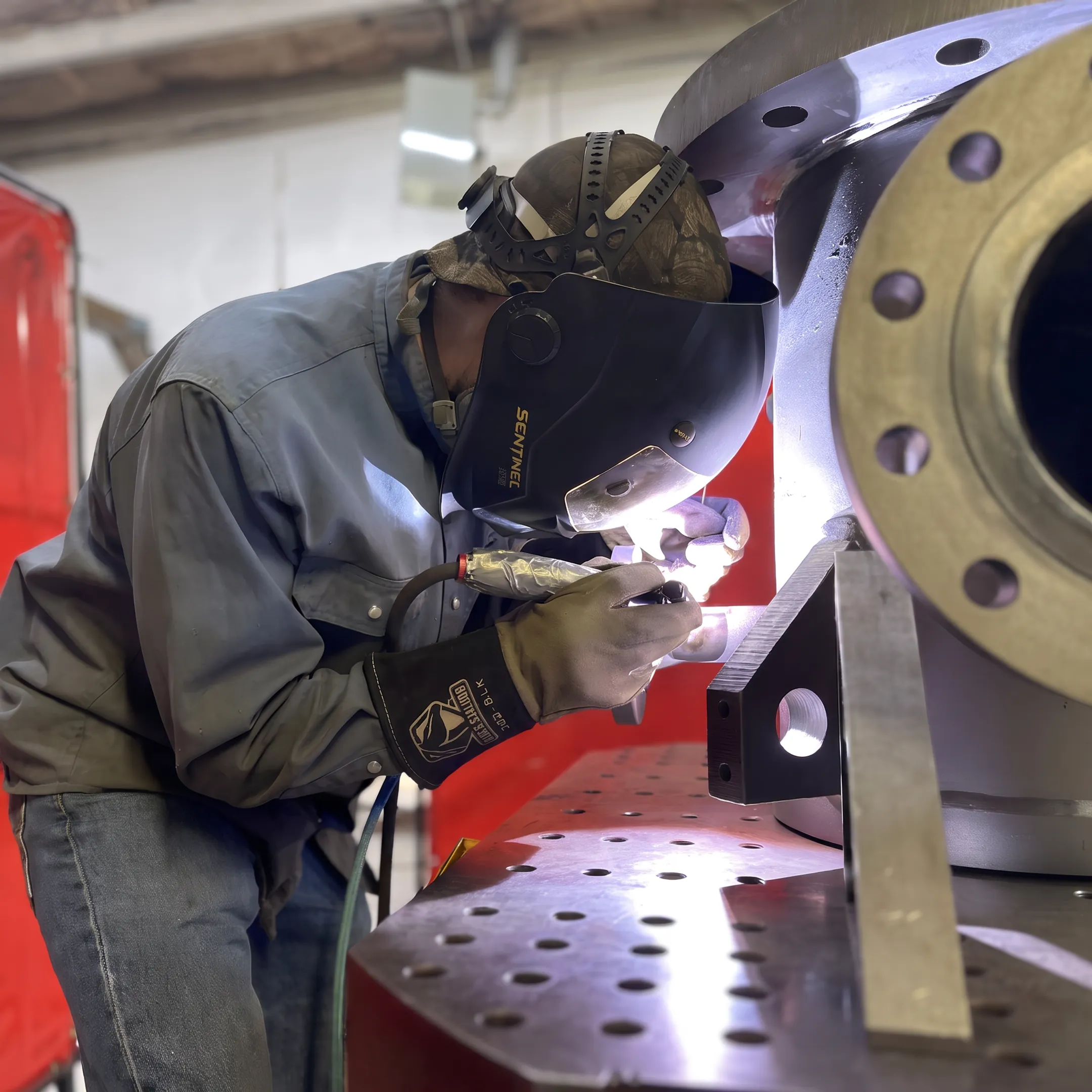 Technician welding a stainless steel industrial piping assembly
