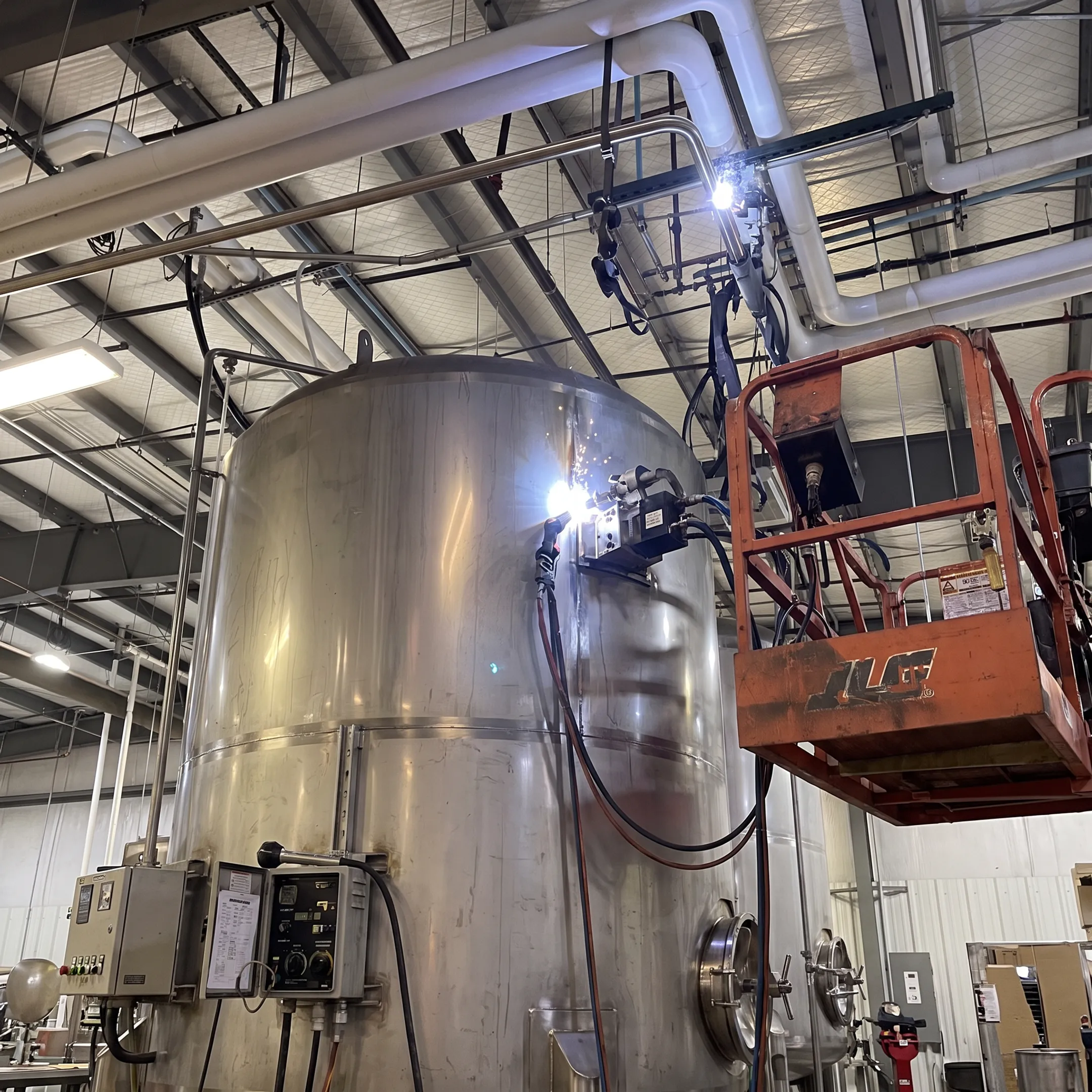 Automated welding machine fabricating a cylindrical metal tank