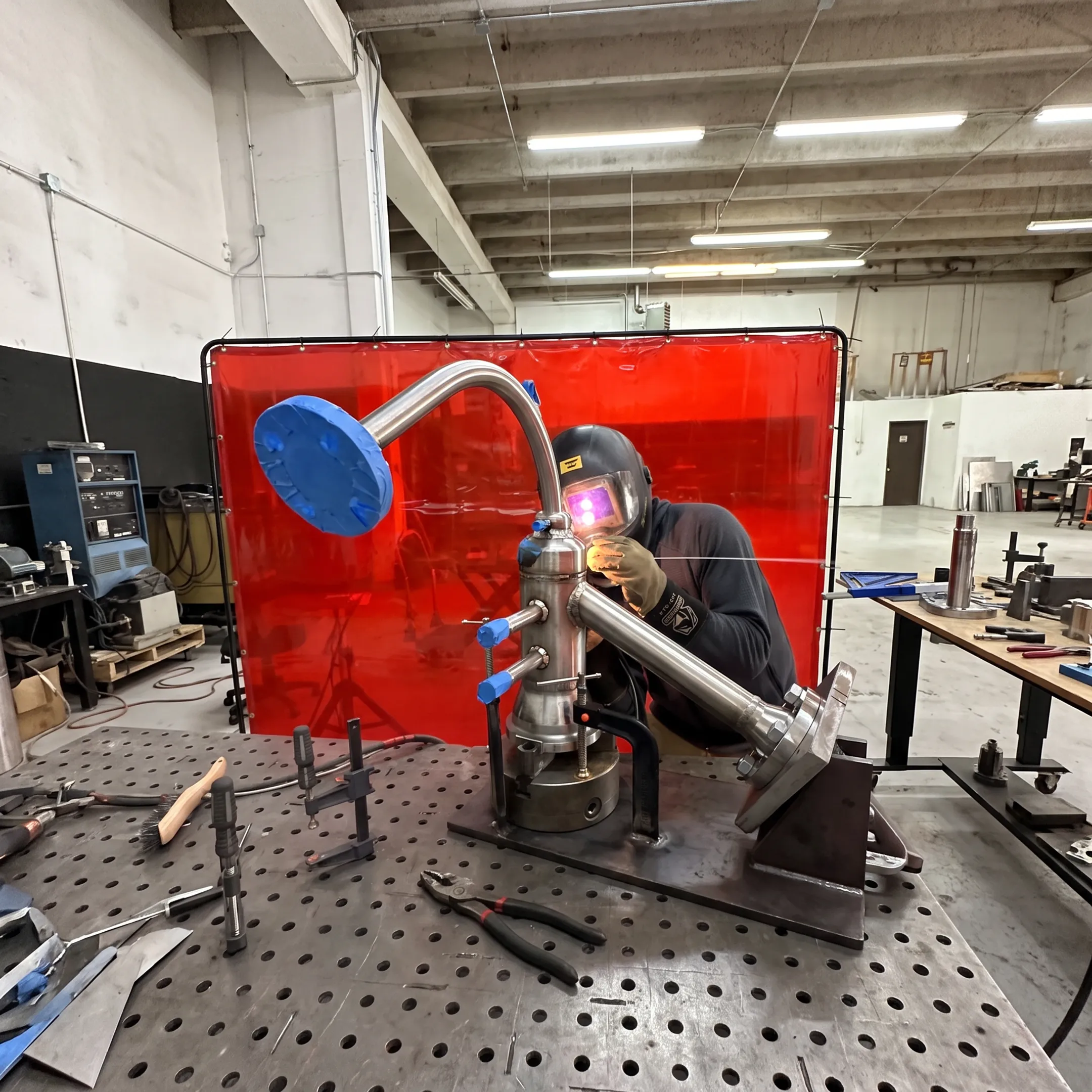 Welder fabricating a custom stainless steel assembly in a precision metalworking shop