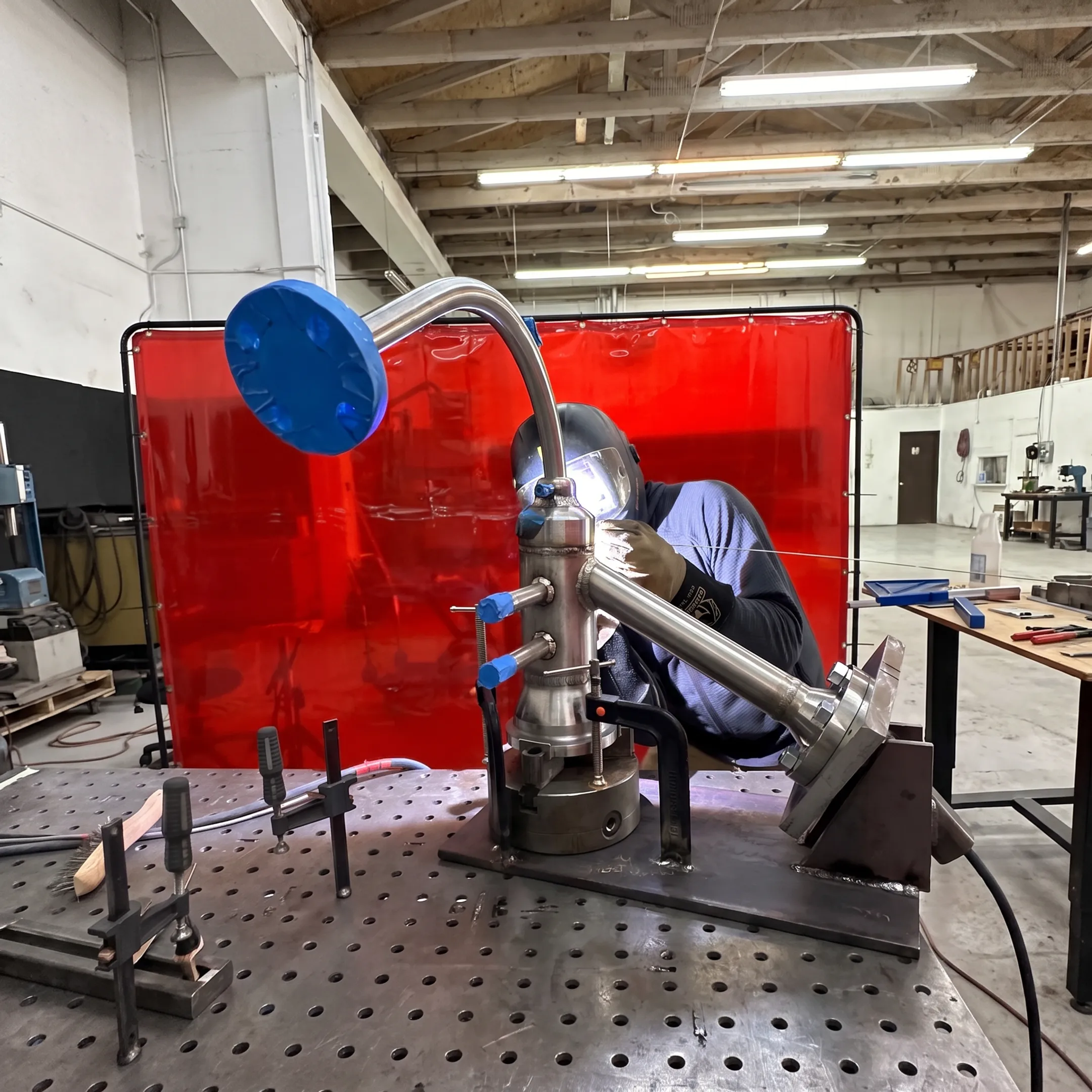 Welder fabricating a precision stainless steel piping assembly