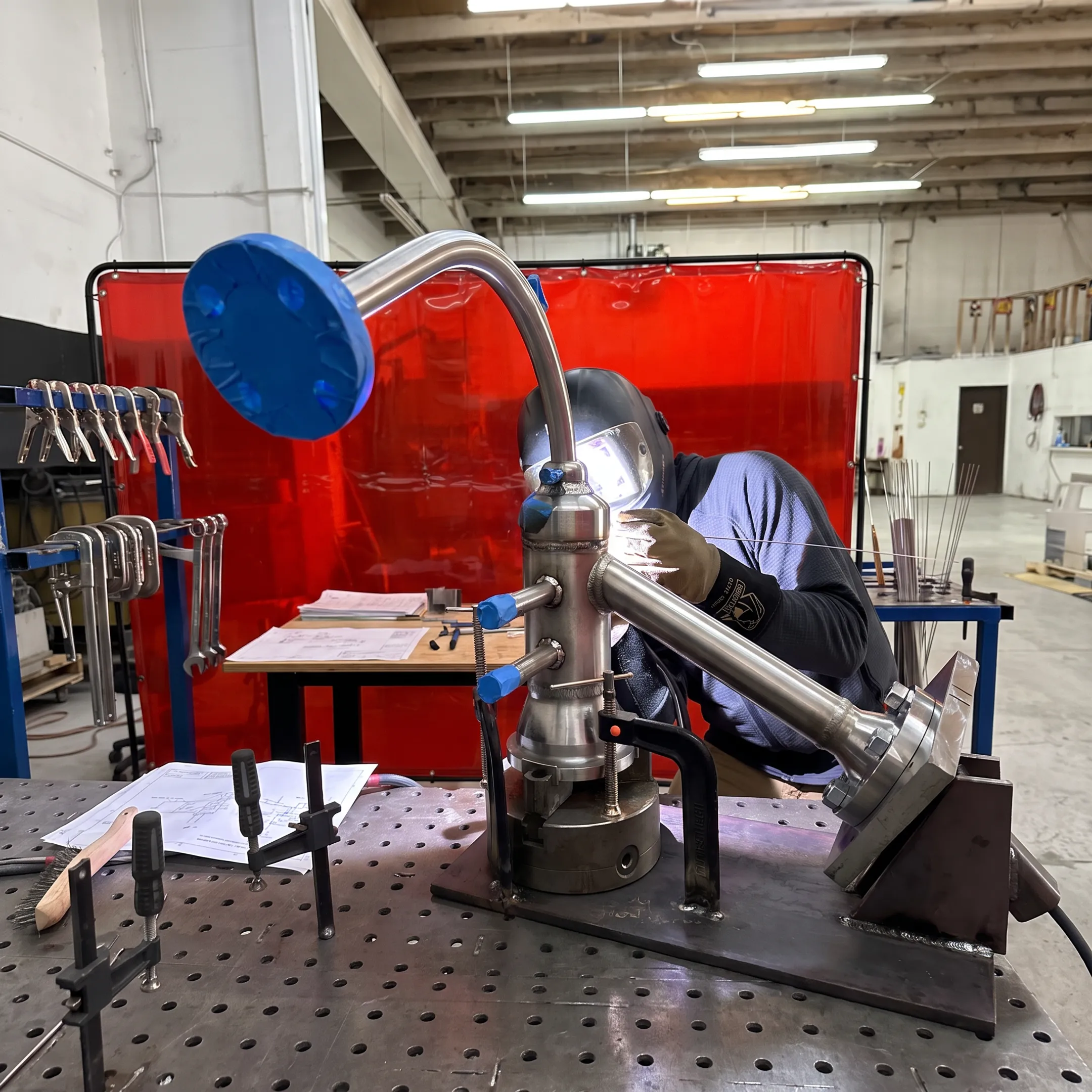 Welder fabricating nickel alloy piping in a controlled metalworking shop