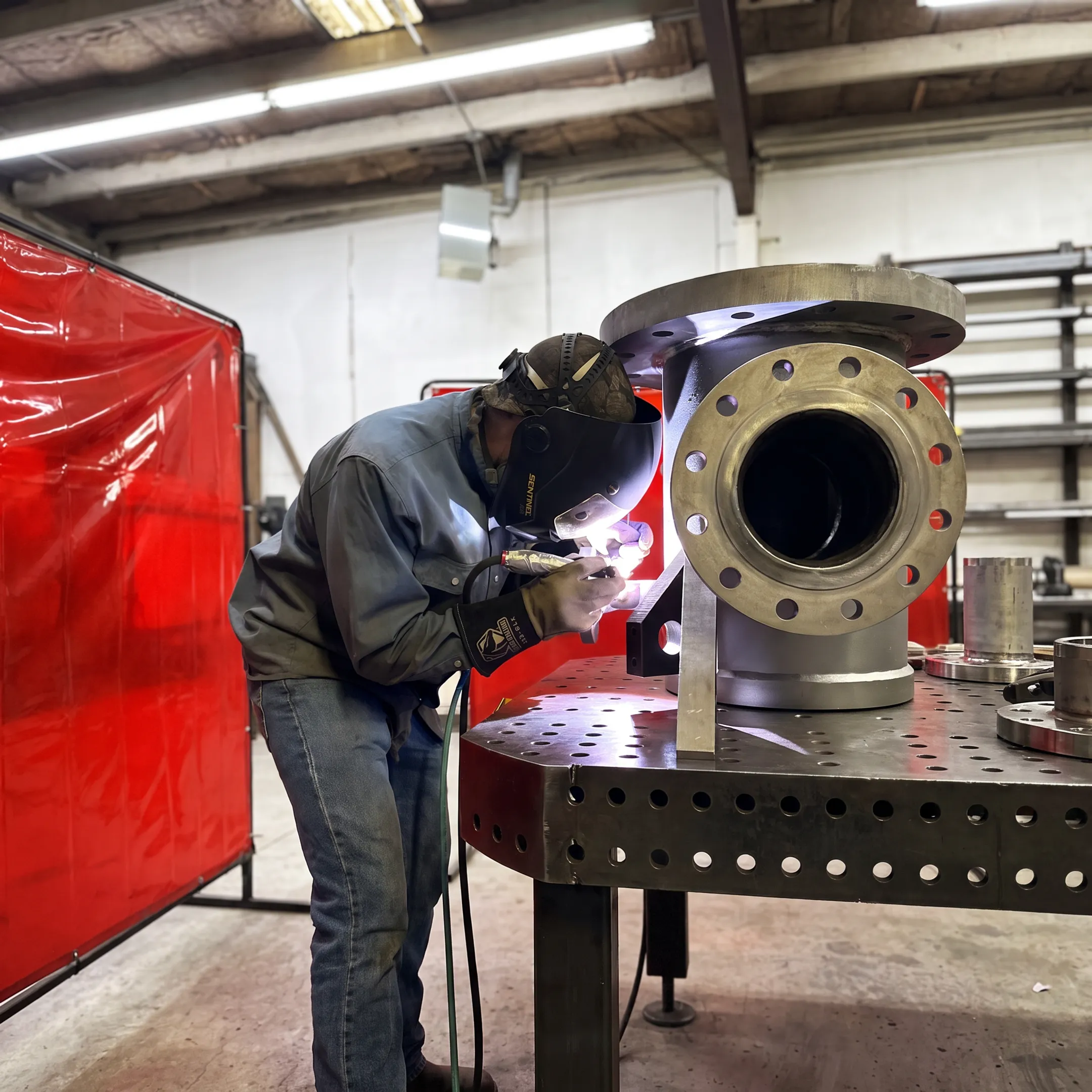 Technicians welding a fabricated industrial tank assembly in a controlled metalworking shop
