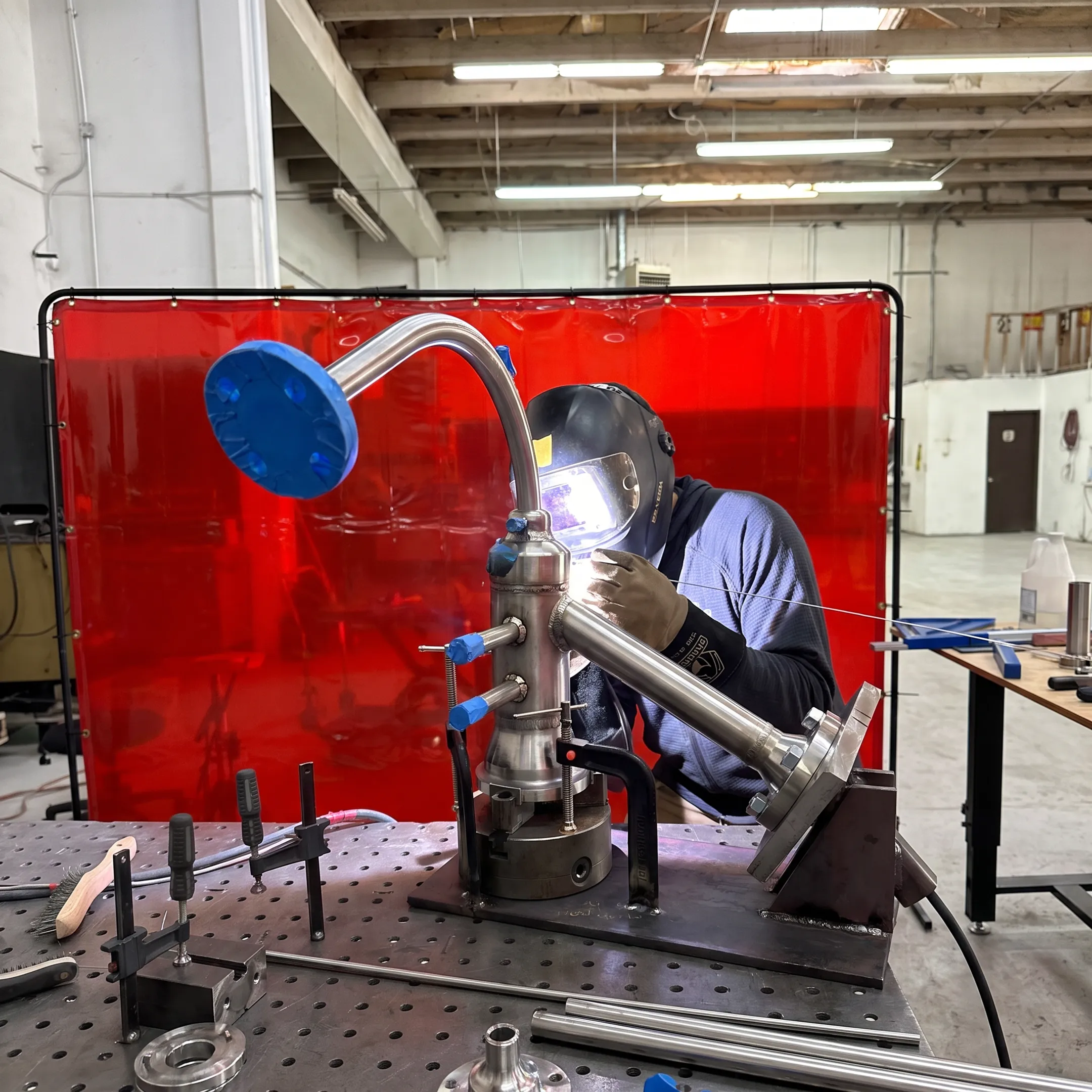 Welder fabricating a precision metal assembly in a controlled workshop