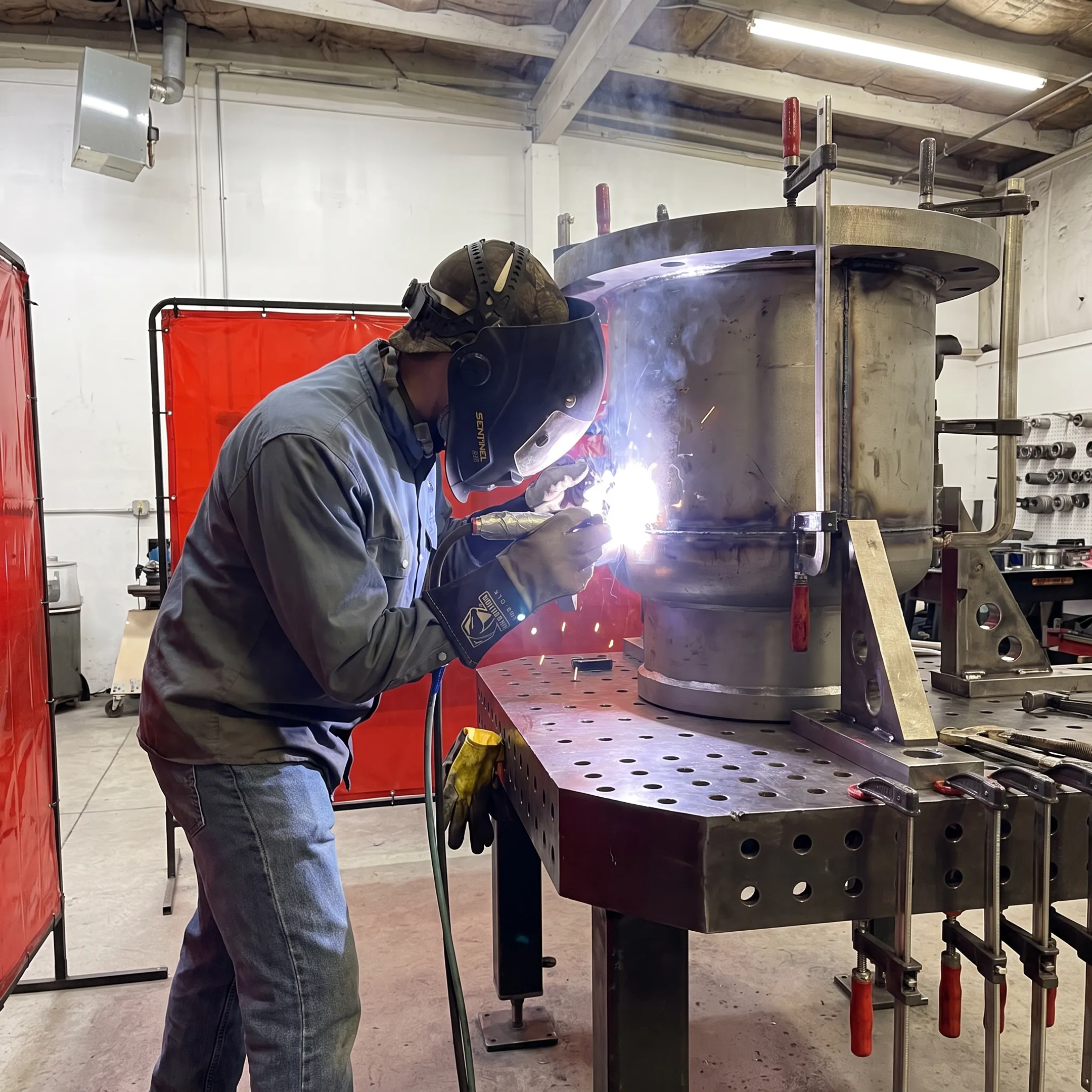 Custom steel storage tank being precision welded in a fabrication shop
