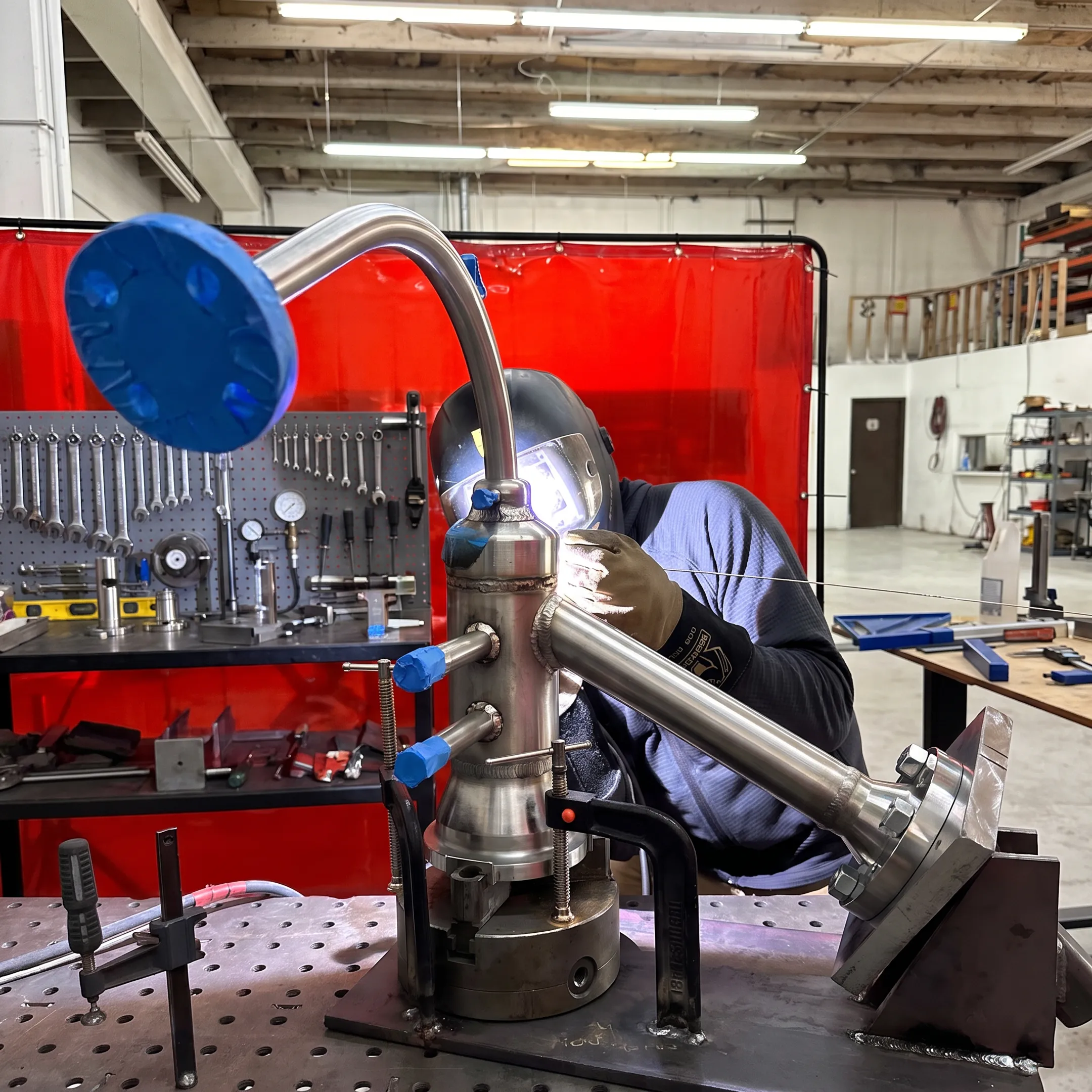 Welder fabricating an industrial stainless steel piping assembly