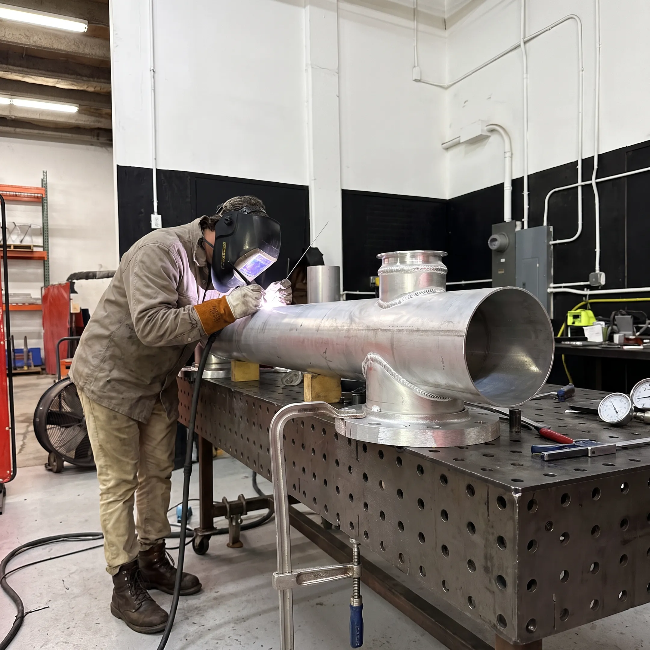 Welder fabricating an aluminum pressure vessel in a precision metalwork shop