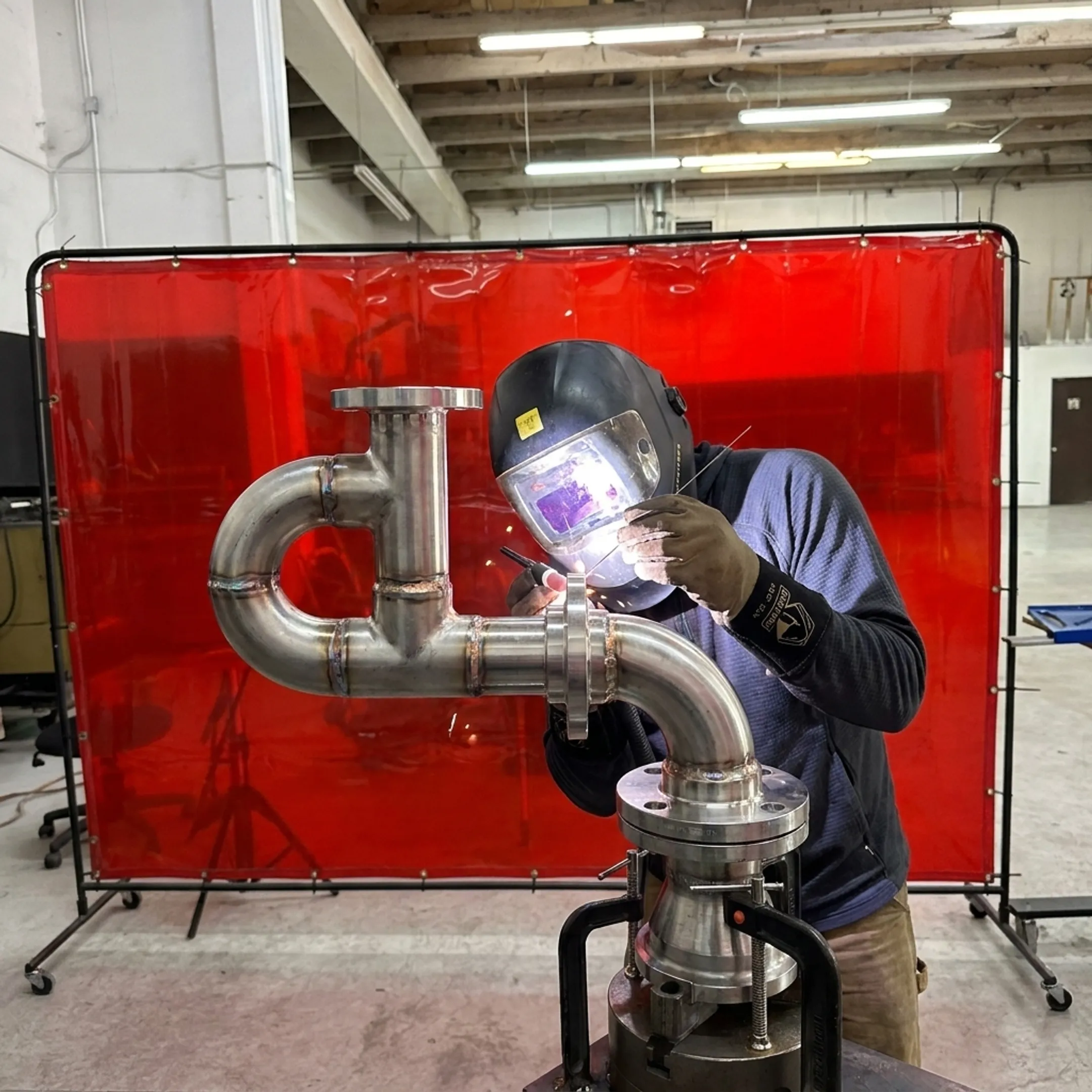 Welder fabricating a stainless steel process piping assembly