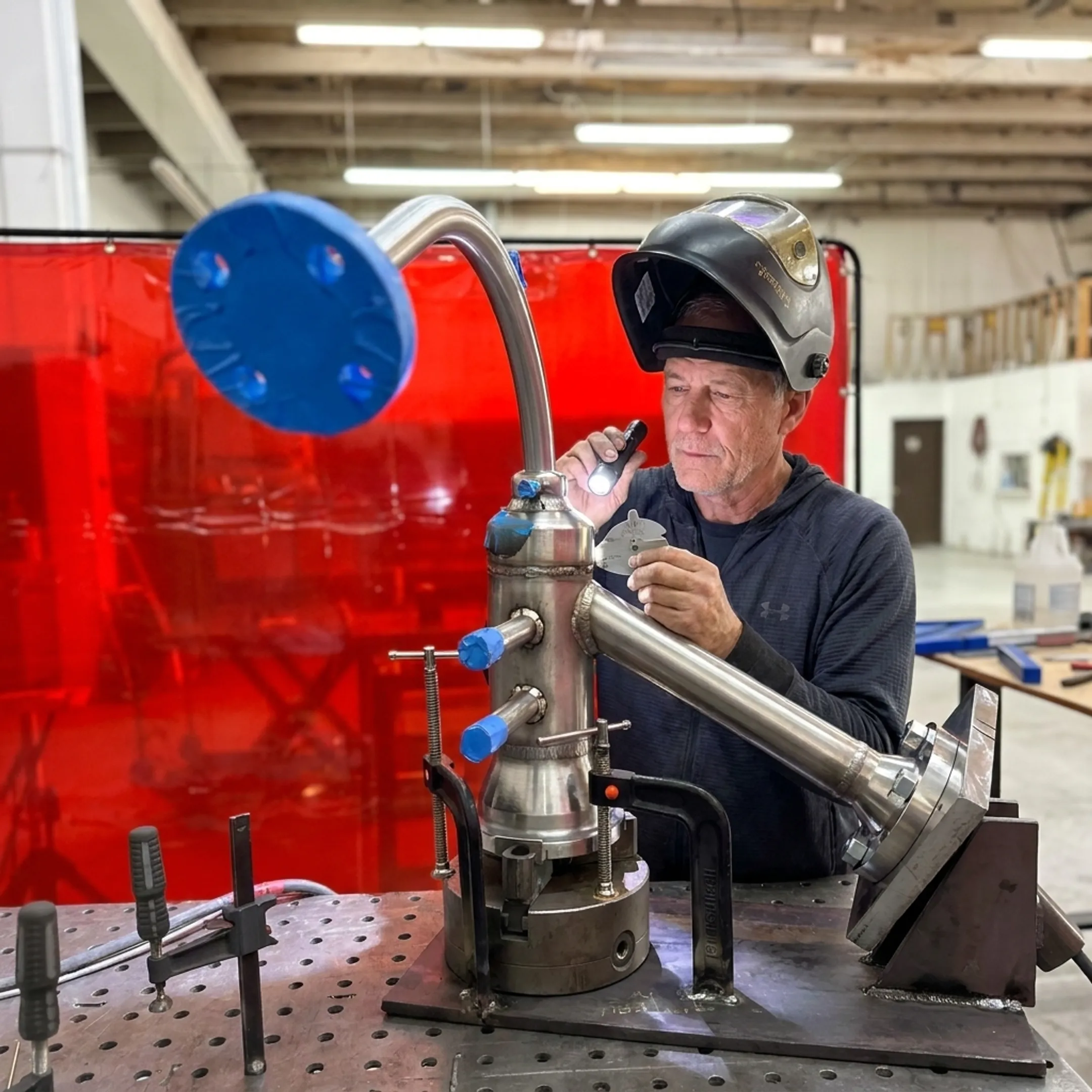 Technician inspecting a stainless steel pressure vessel weld