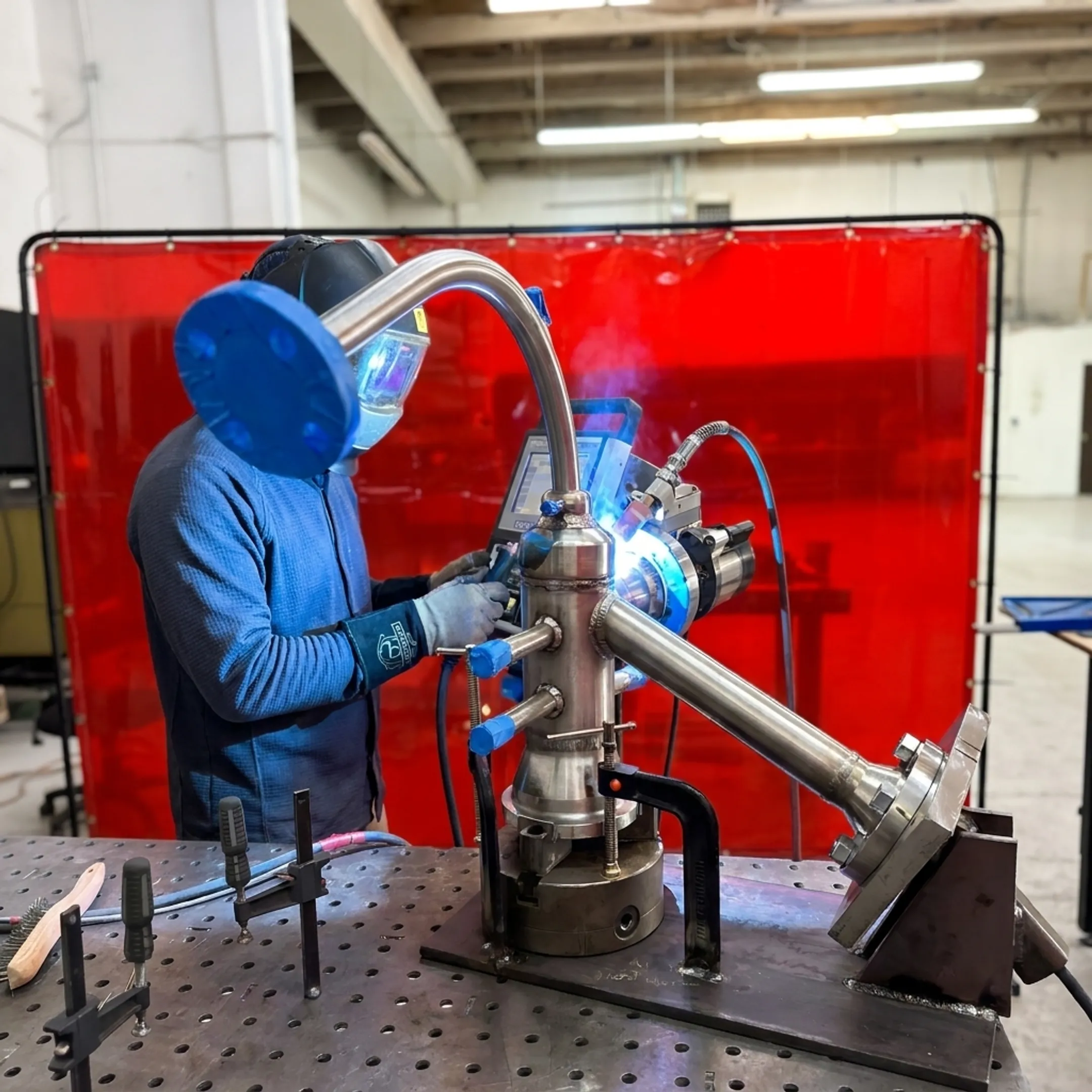 Technician monitoring automated welding of a precision industrial component