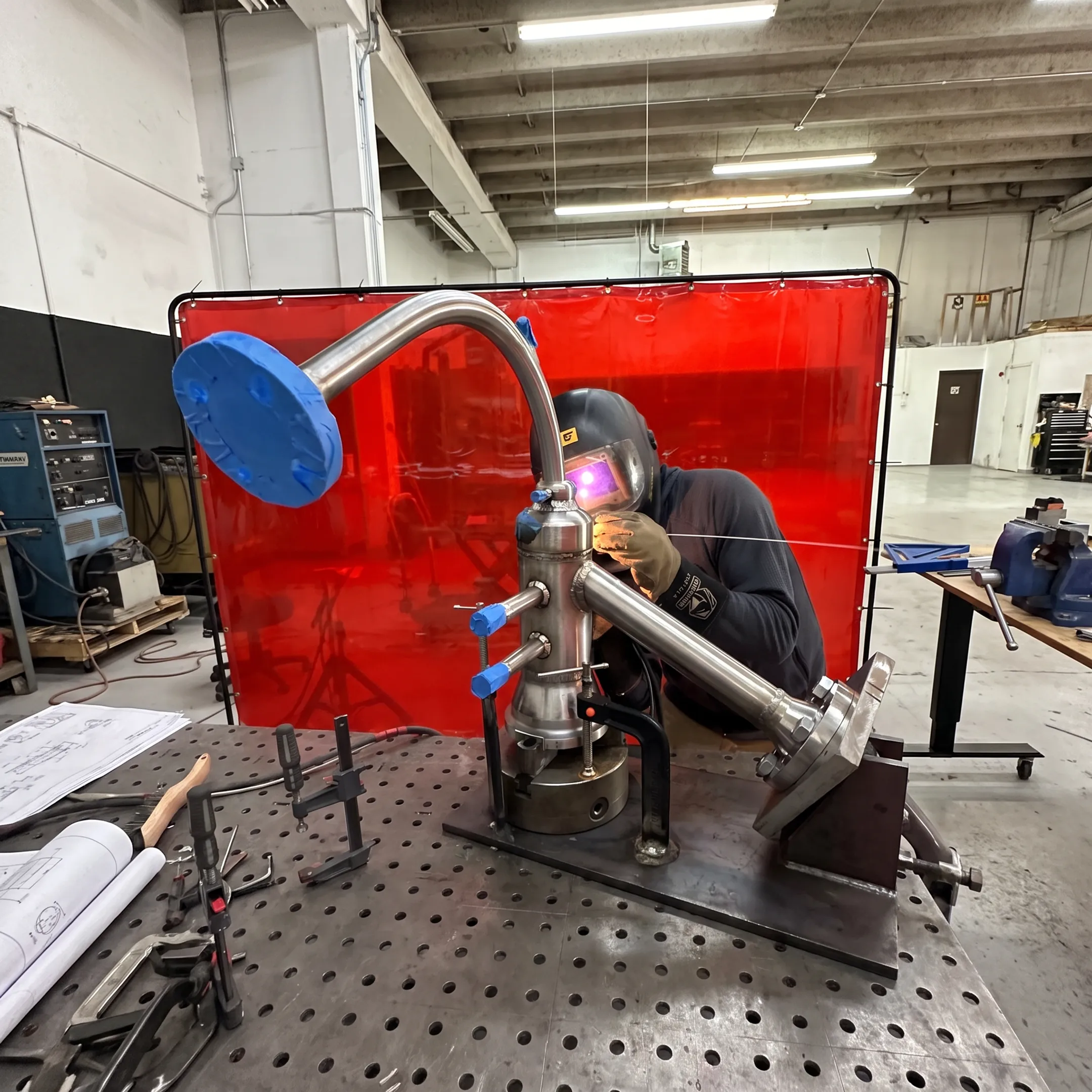 Technician welding a precision metal assembly in a fabrication shop
