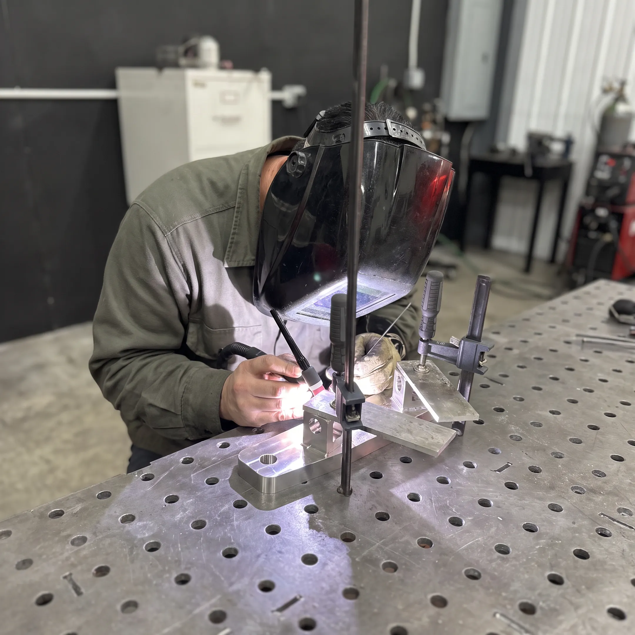 Welder fabricating a precision metal assembly in a controlled workshop