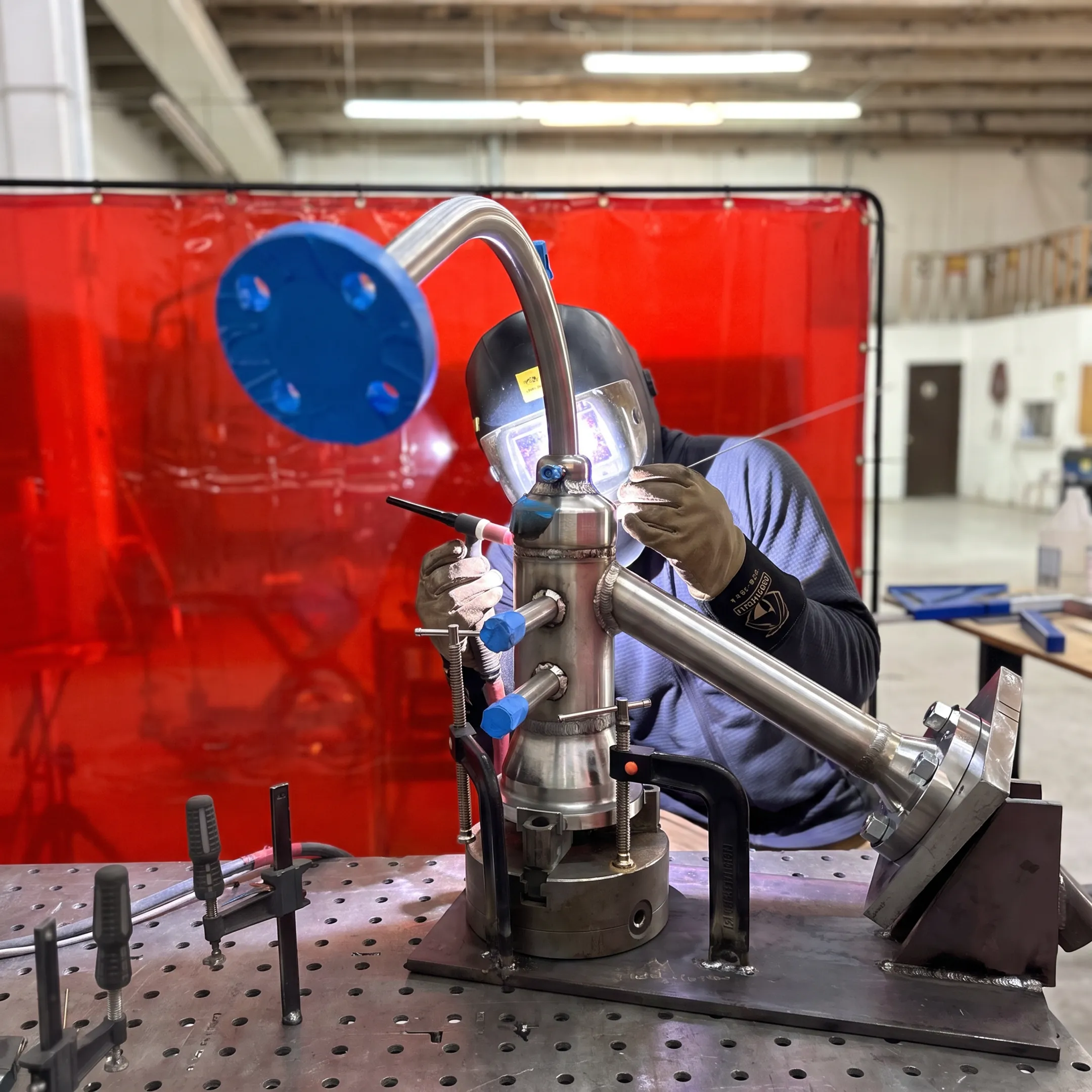 Welder performing precision TIG welding on a metal assembly in a controlled fabrication shop