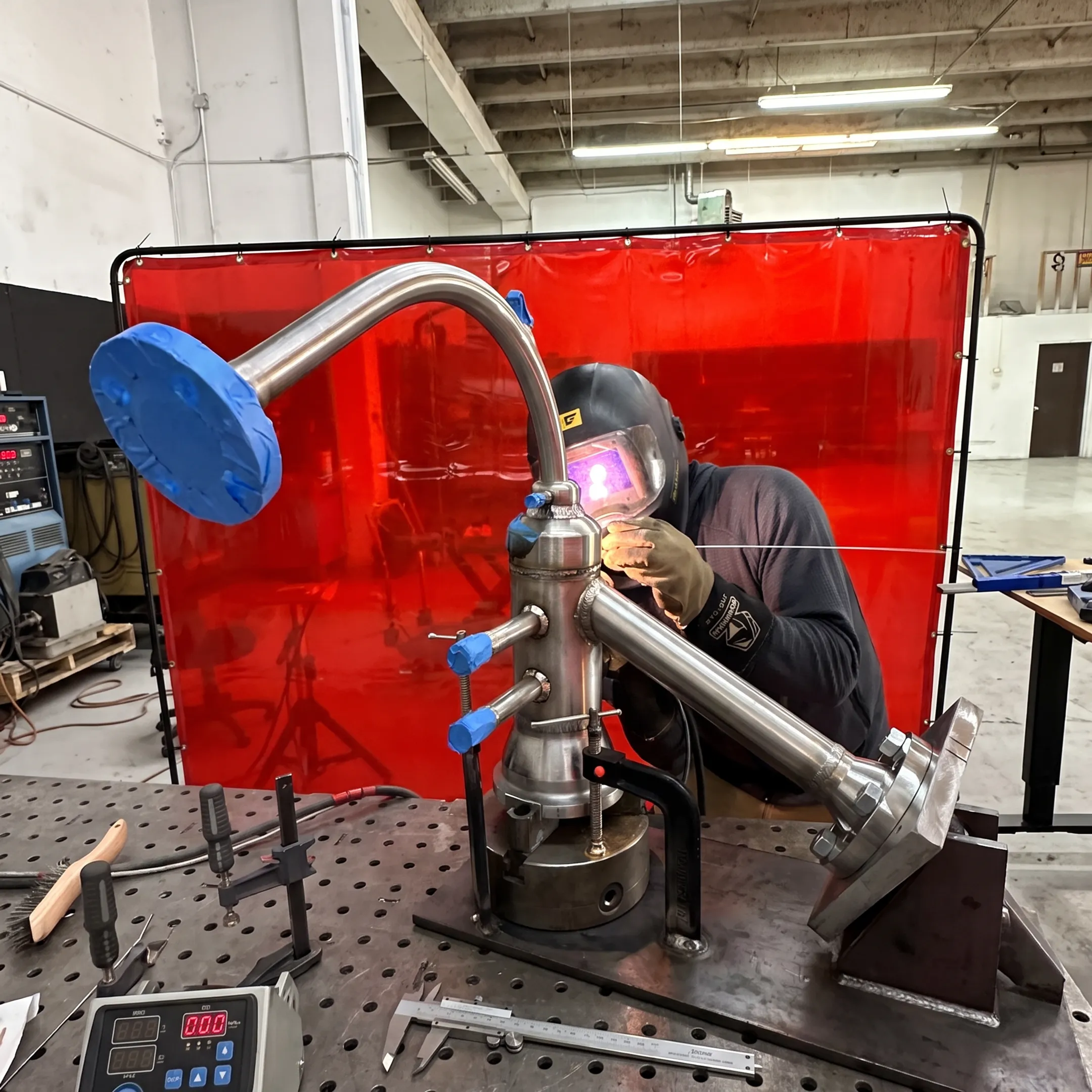 Technician welding a custom pipe assembly in a precision fabrication shop