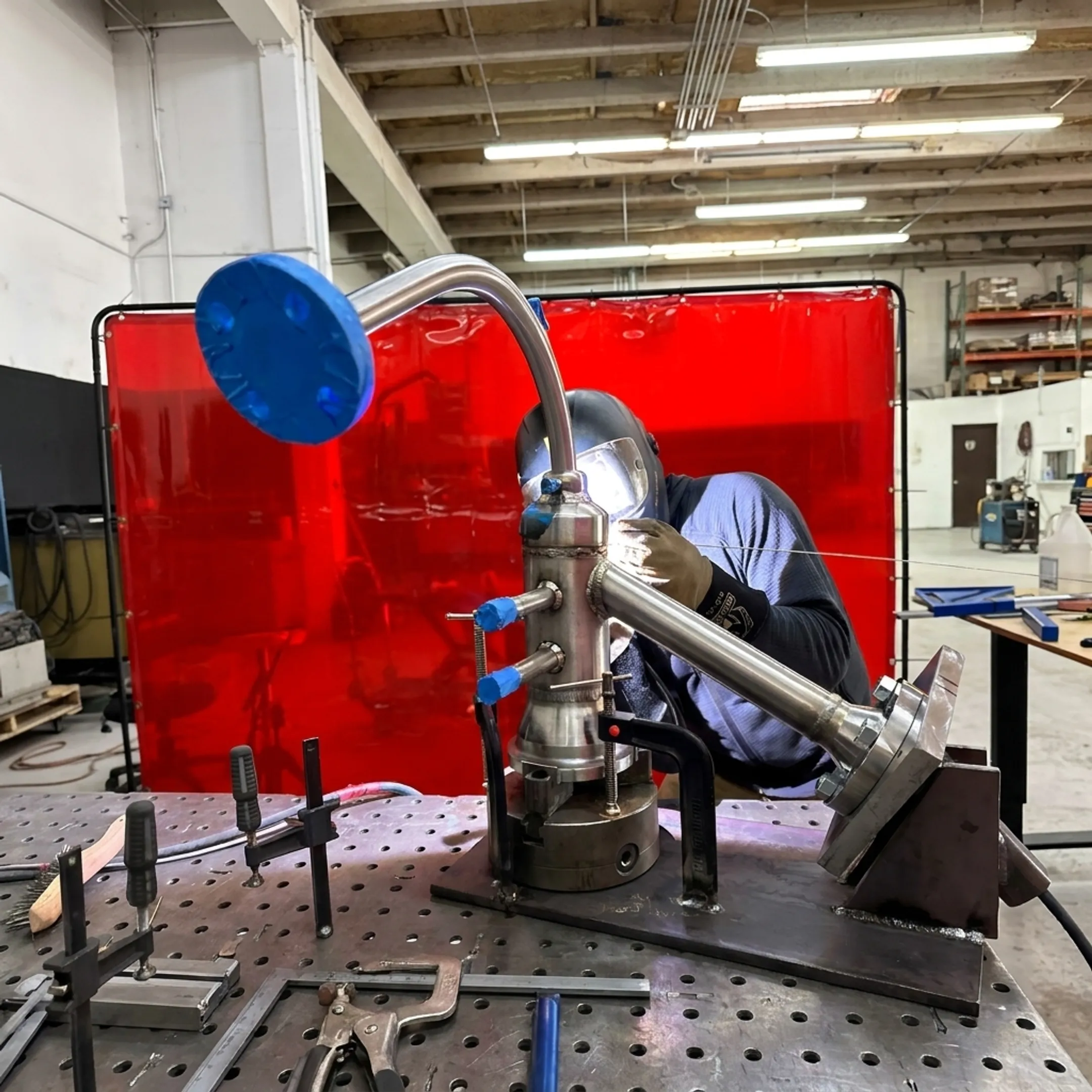 Fabricator welding a precision metal assembly in a controlled shop environment