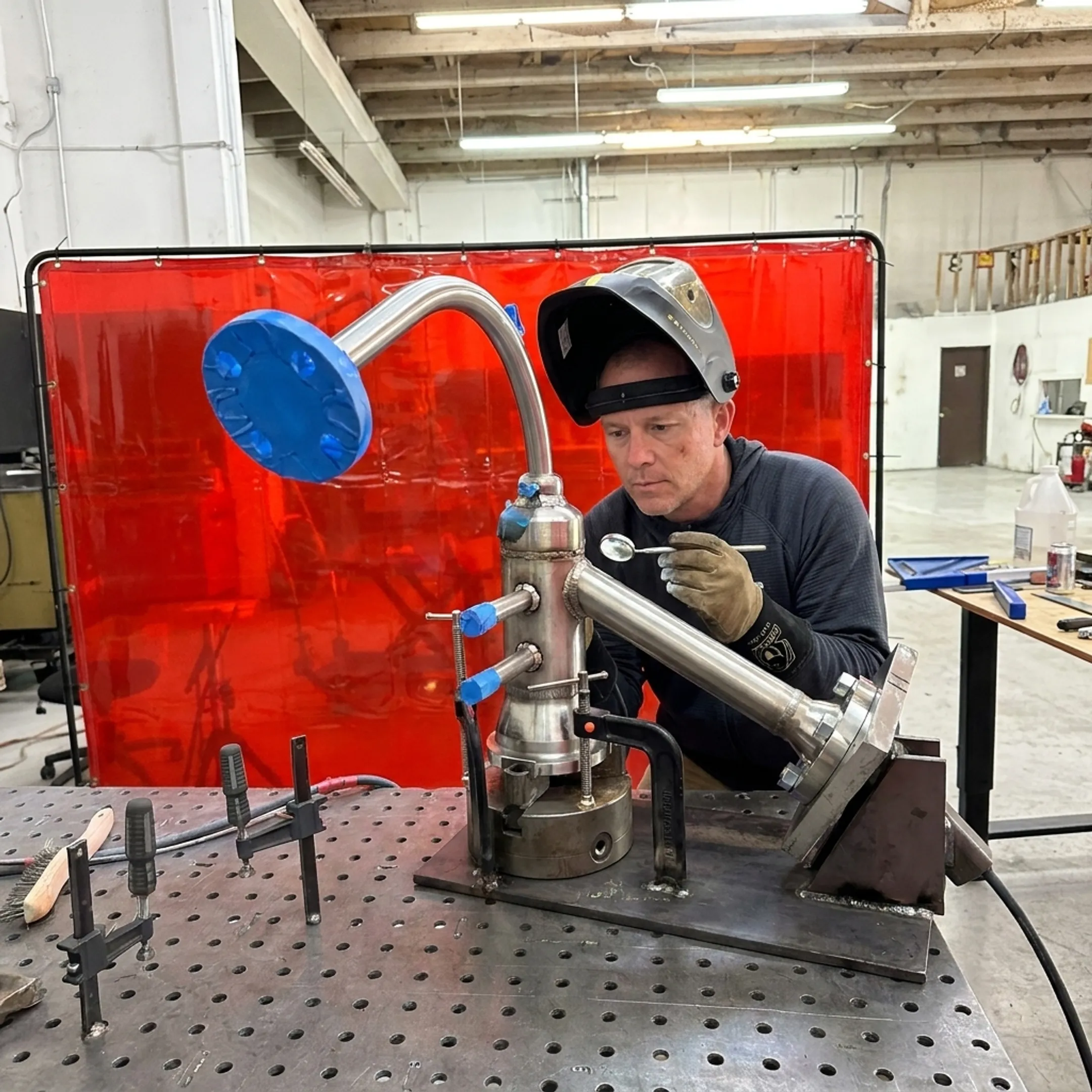 Welder inspecting an orbital weld on a precision metal component