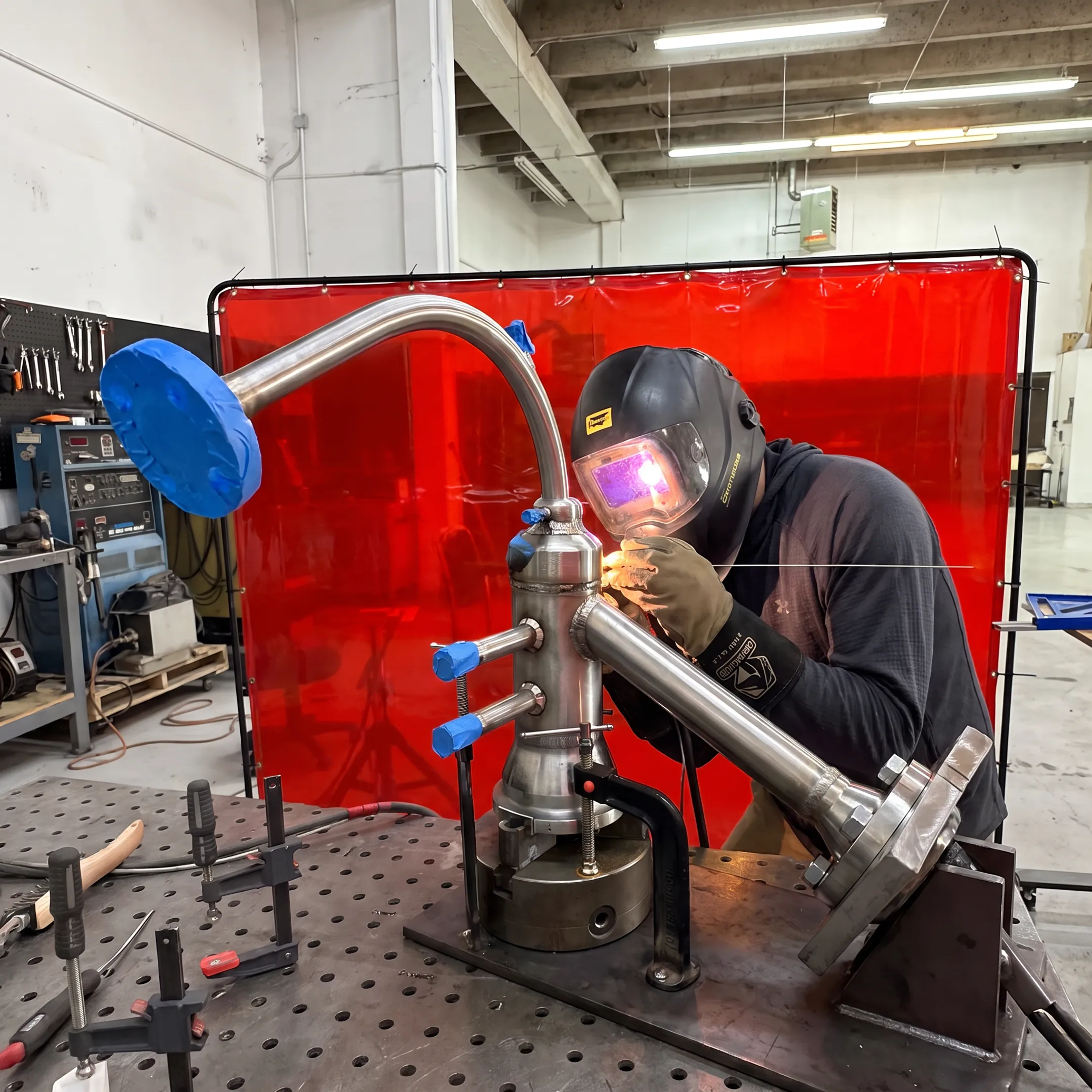 Welder fabricating a precision metal assembly in a controlled shop