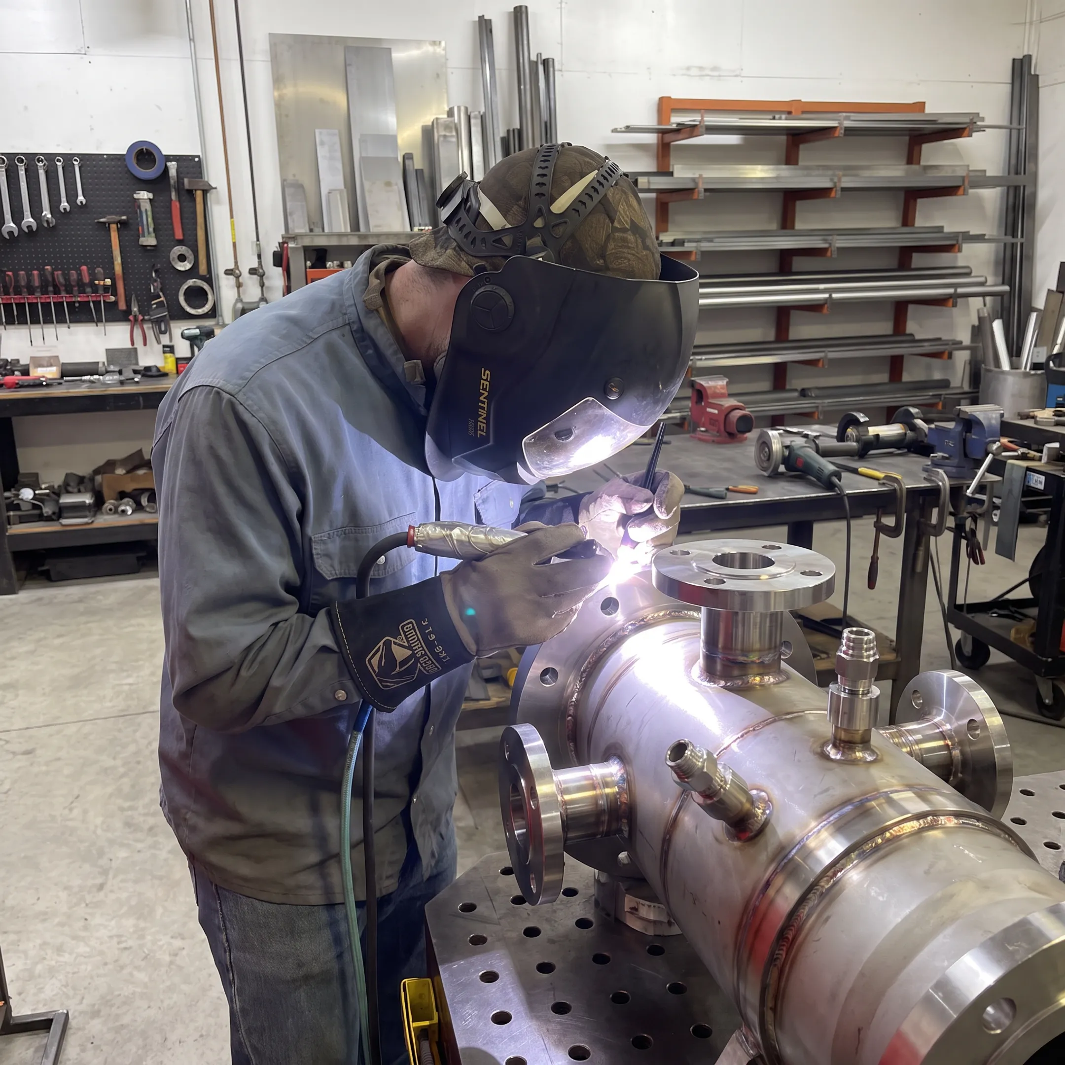 Precision metal assembly being TIG welded in a controlled fabrication workshop