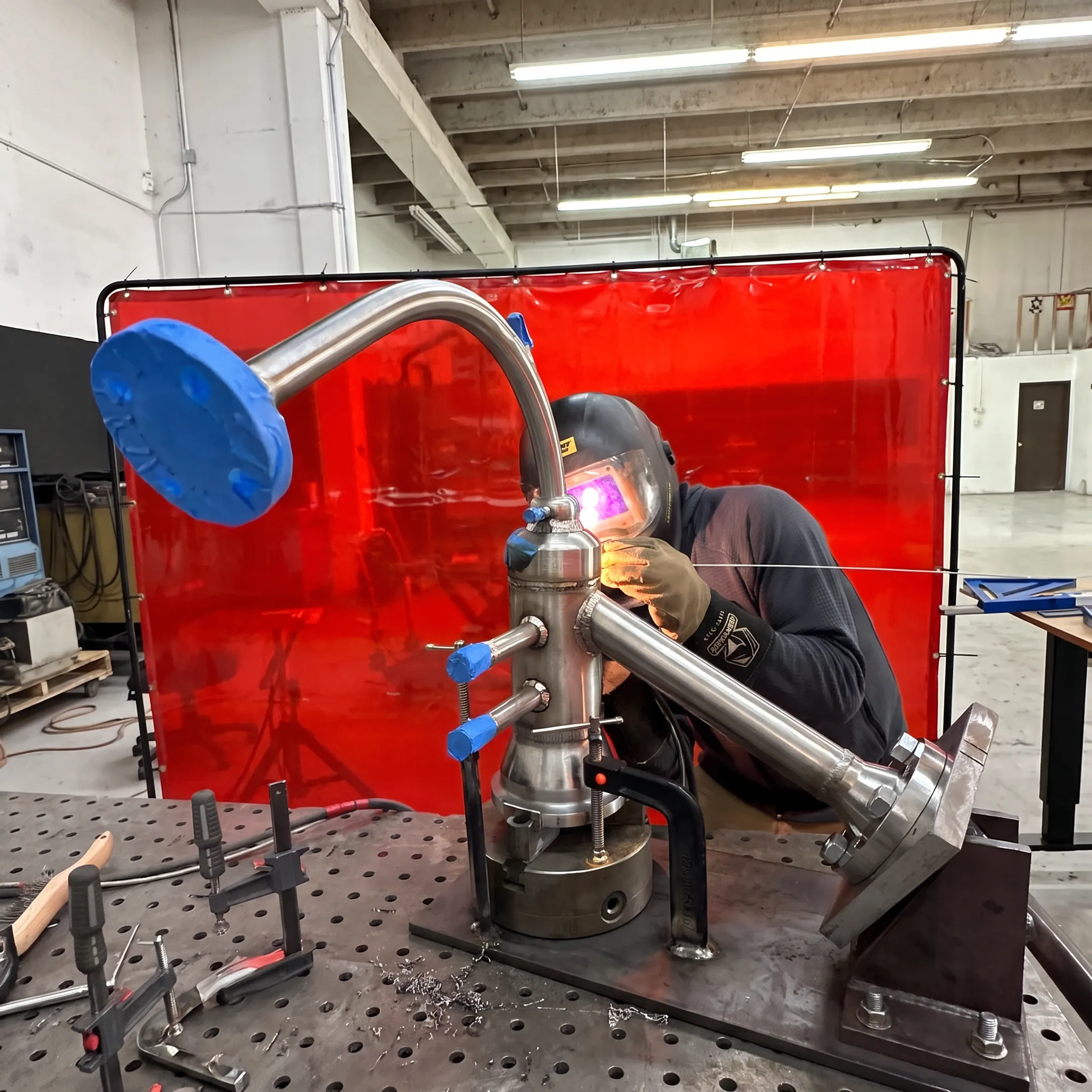 Welder fabricating a custom stainless steel assembly in a precision workshop
