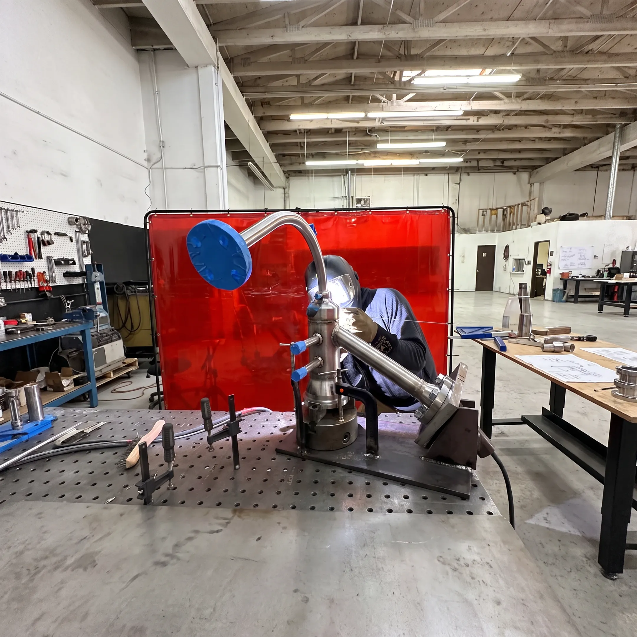 Fabricator welding a custom industrial piping assembly