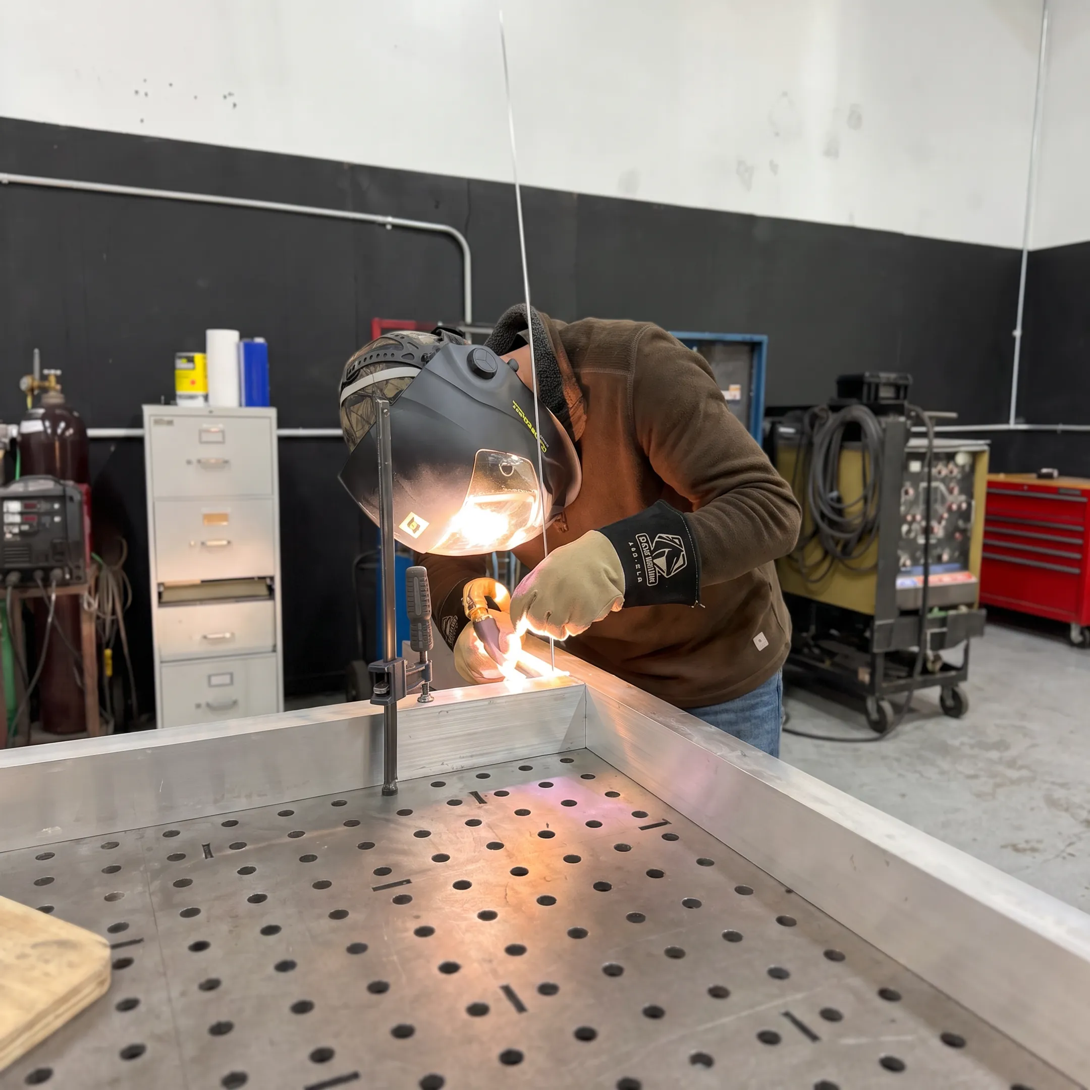 Technician TIG welding an aluminum component in a precision fabrication shop