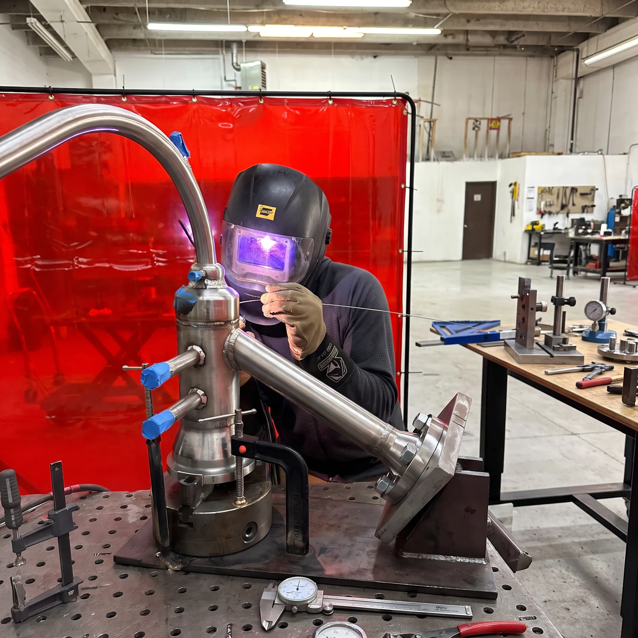 Welder fabricating a precision stainless steel pipe assembly