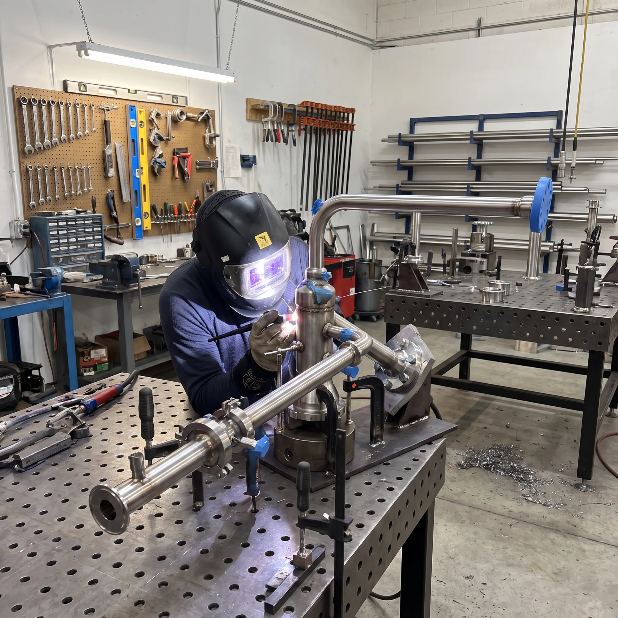 Welder fabricating stainless steel process piping in a controlled workshop
