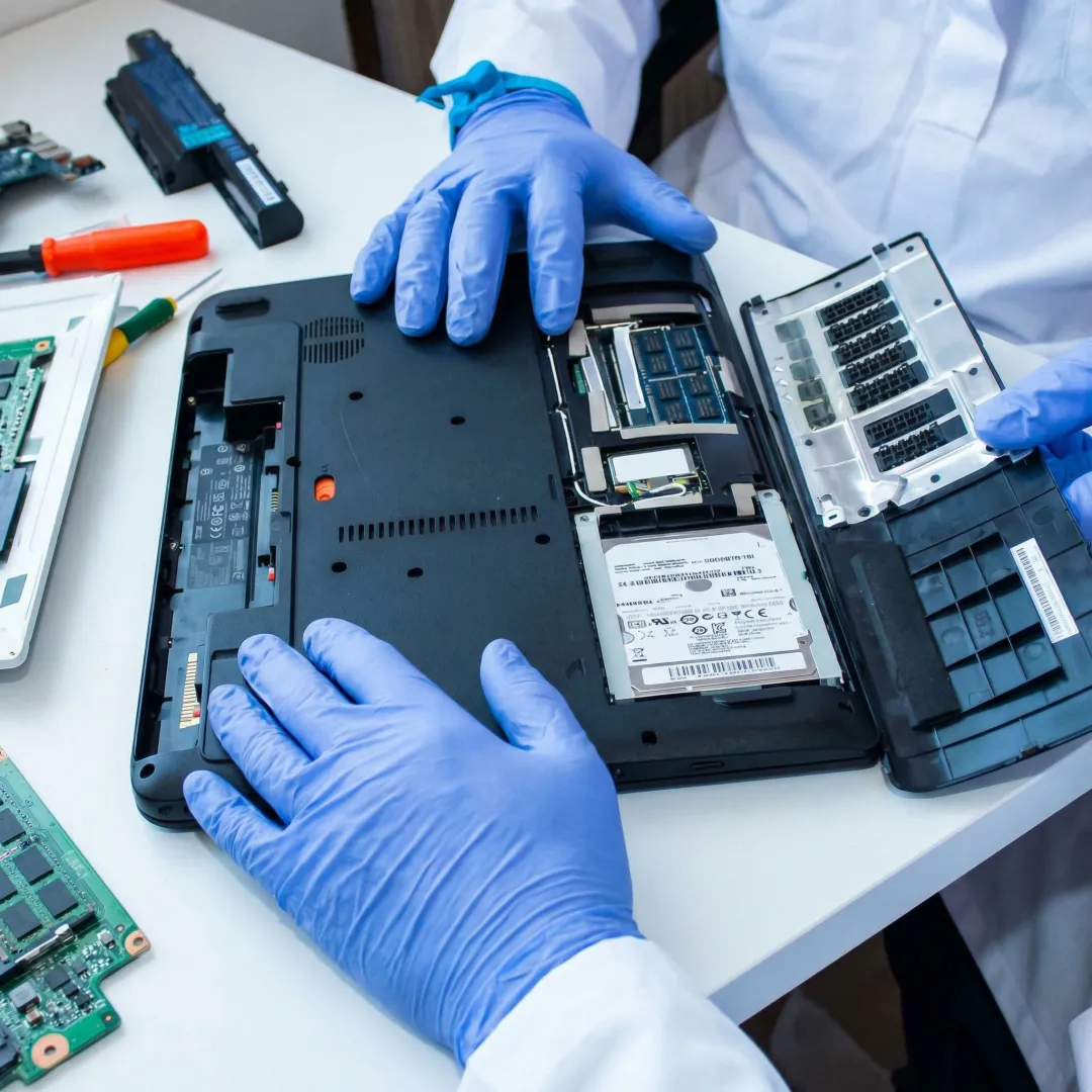 Technician repairing a laptop computer at a professional workbench