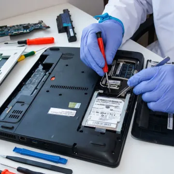 Technician performing hard drive repair on a laptop computer