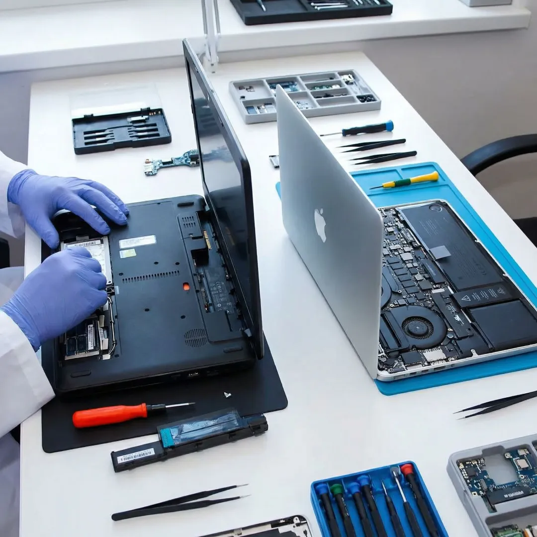 Technician repairing a Mac and PC laptop on a clean workbench