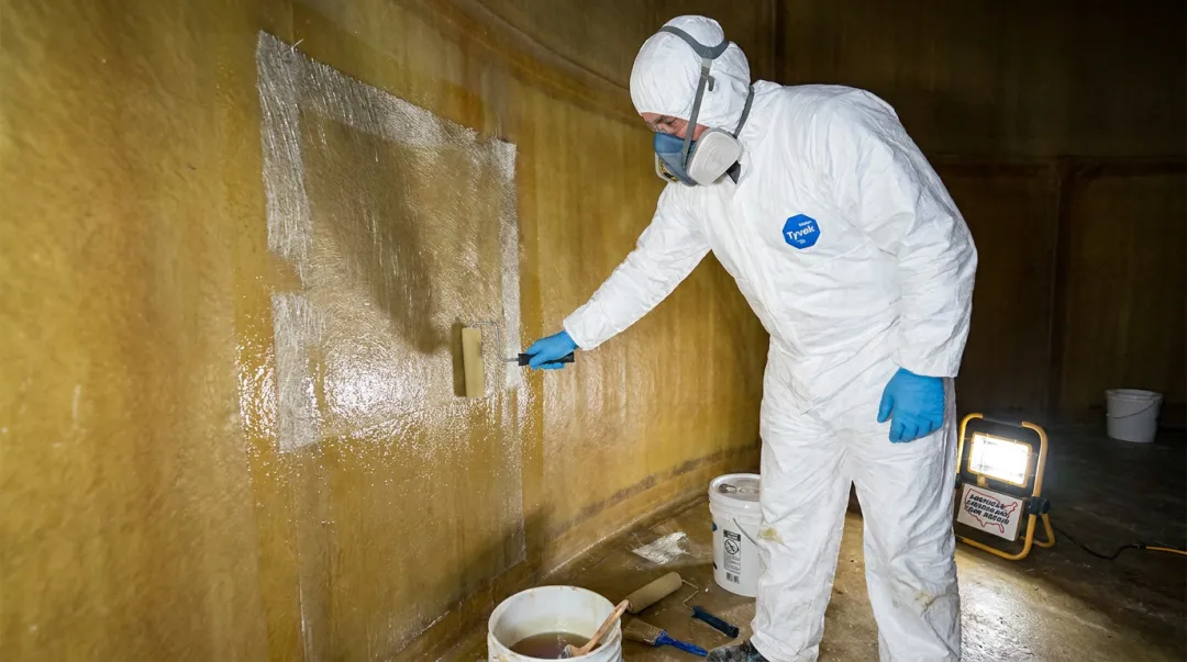 AFTR technician applying fiberglass liner repair resin inside industrial FRP tank