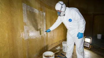 AFTR technician applying fiberglass liner repair resin inside industrial FRP tank