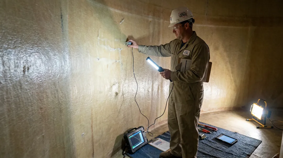 AFTR inspector performing ultrasonic testing on fiberglass storage tank lining interior
