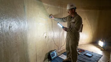AFTR inspector performing ultrasonic testing on fiberglass storage tank lining interior