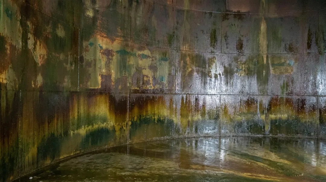 Wastewater treatment FRP tank interior showing microbial biofilm and liner degradation