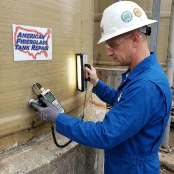Inspector using testing equipment on an FRP tank wall