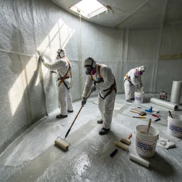 FRP tank repair crew applying fiberglass laminate