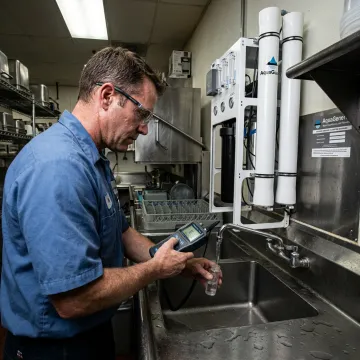 Specialist testing restaurant water at a sink