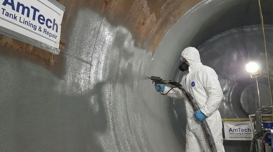Professional tank lining technician applying engineered coating inside large steel pressure vessel